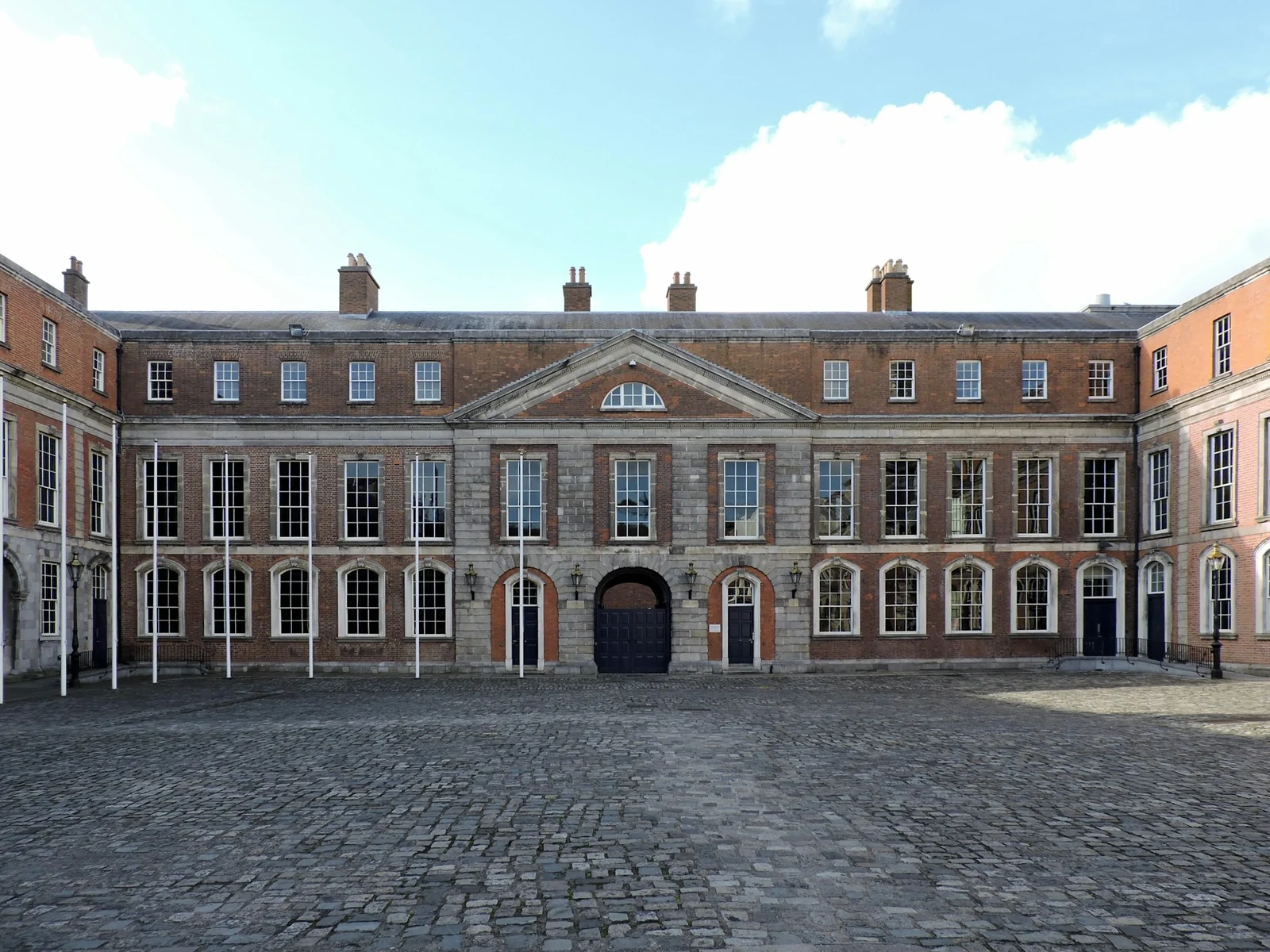 Sunlit State Apartments and dry cobbled Upper Yard at Dublin Castle beneath a blue sky