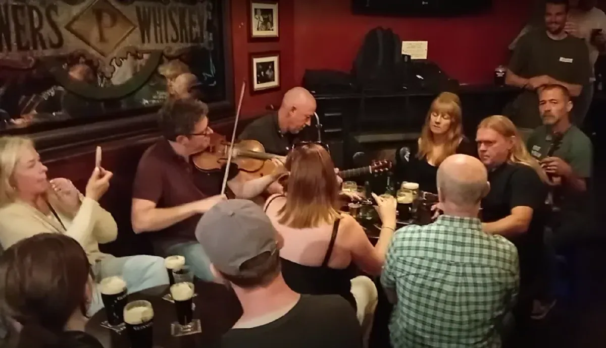 Musicians playing fiddle and guitar during a session in a Dublin pub