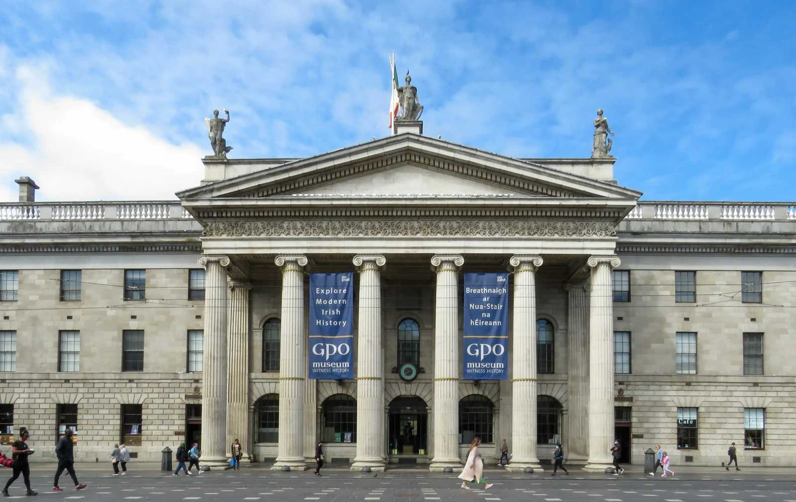 People walking past the GPO on O’Connell Street under a blue sky, the headquarters of the 1916 Easter Rising